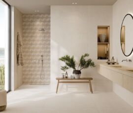 Sofisticato ambiente bagno. A pavimento la finitura Ivory 120x120, sulla parete lavabo spicca Docks, nella finitura Ivory. Si tratta di un motivo decorativo (30x60cm) che alterna formati rettangolari differenti, per aggiungere dinamismo e originalità alle superfici. Il lavabo è rivestito con Grace Beige, nel grande formato 120x278. La parete doccia è realizzata con il Mosaico Rombi (30,5x35,2), variante White Ivory, che crea un effetto ottico tridimensionale