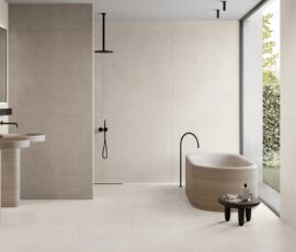 Ambiente bagno. Protagonista è la finitura White, visibile a pavimento e a parete (a sinistra e in fondo), rispettivamente 60x120 e 120x278. Sulla parete a destra spicca Plisse (20x120), che restituisce un gradevole effetto decorativo. La quinta della doccia è rivestita con il decoro Weave (60x120), che rievoca le texture Art Decò, nella variante Clay